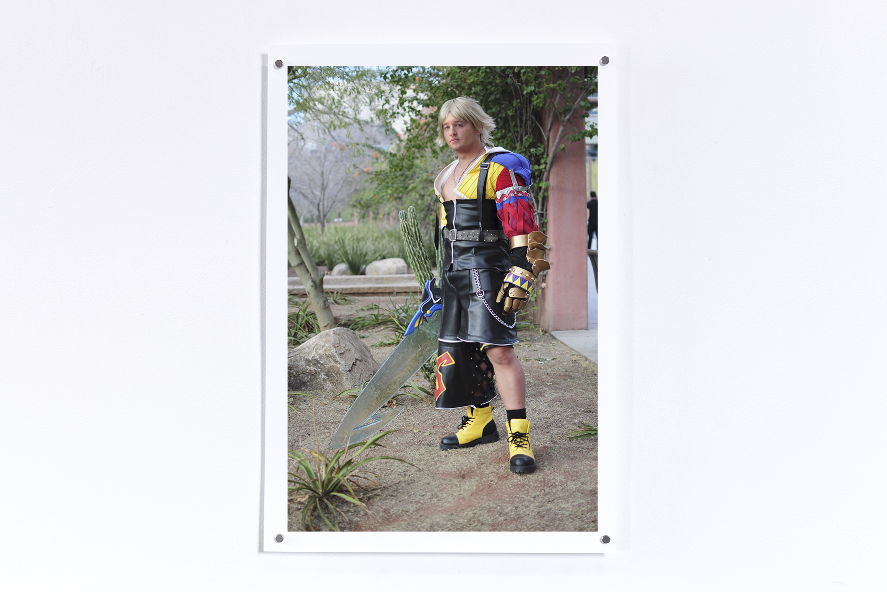 Print hung on a white wall of Tidus from Final Fantasy 10 with a swrod with Jesse's face superimposed on the character